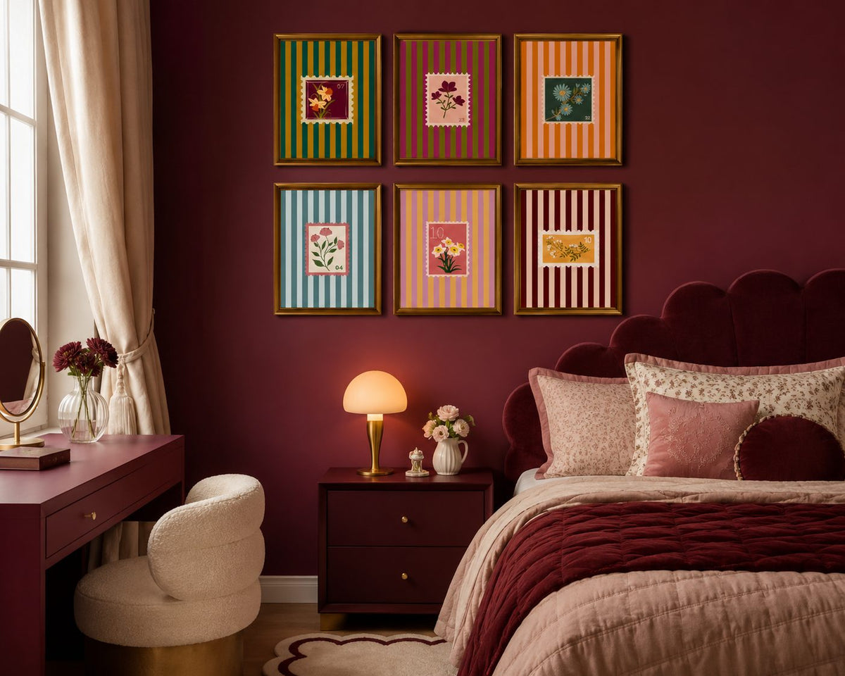 Framed salon style gallery wall of striped botanical prints on a deep maroon bedroom wall